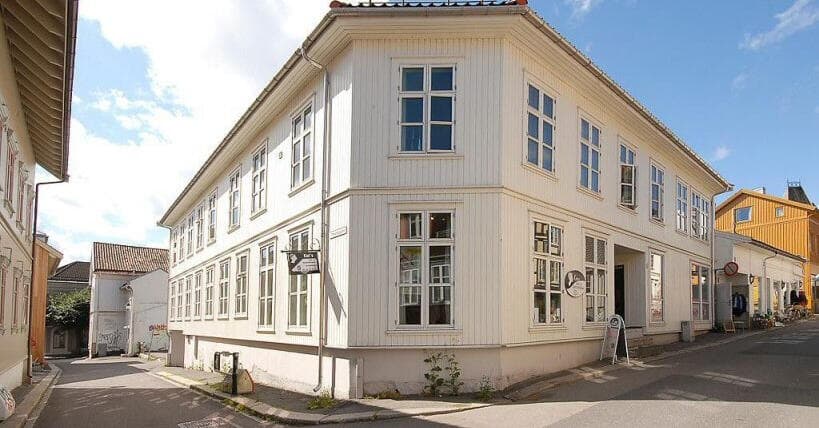Hvitt trehus på hjørnet av Øvre Langgate 34 i Tønsberg, en solrik dag.